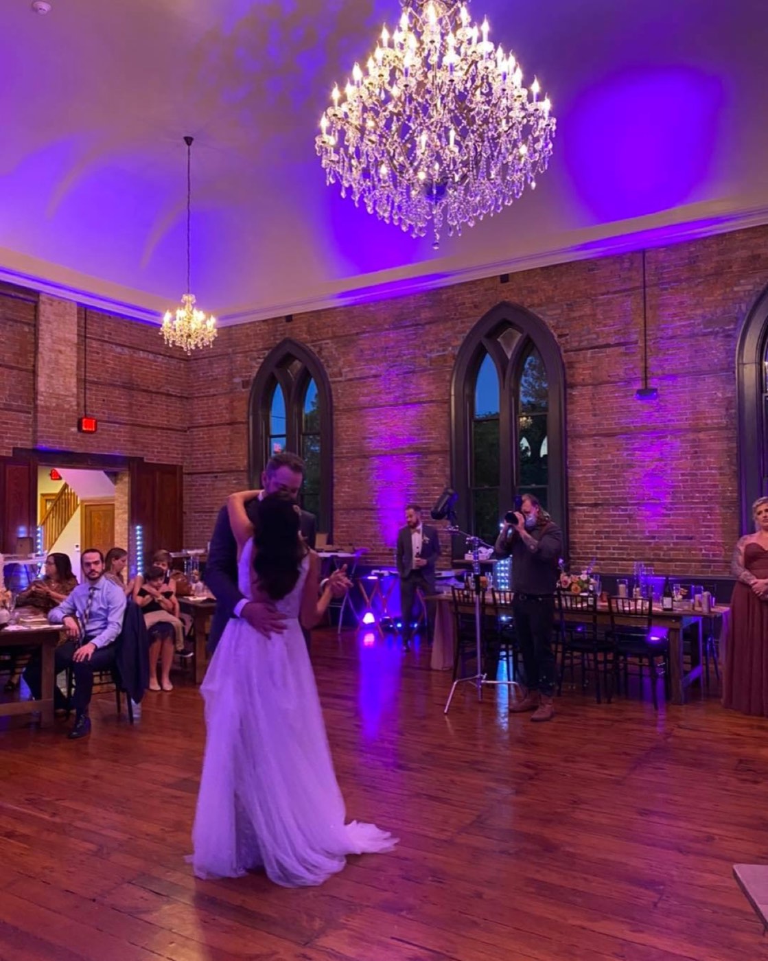 A first dance under a chandelier with purple uplighting